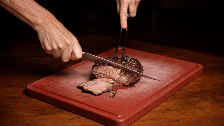 Corte de Chateaubriand de solomillo de buey siendo trinchado con cuchillo sobre una tabla de cortar.