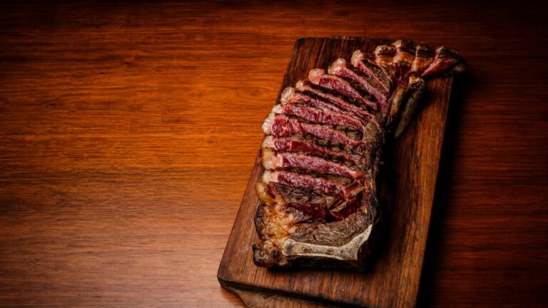 Chuletón de vacuno Rubia Gallega con maduración dry-aged troceado y presentado sobre tabla de madera.